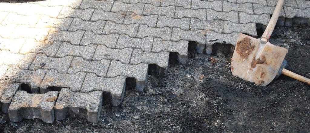 Aufgenommenes Verbundpflaster, daneben ein Spaten im freigelegten Untergrund.