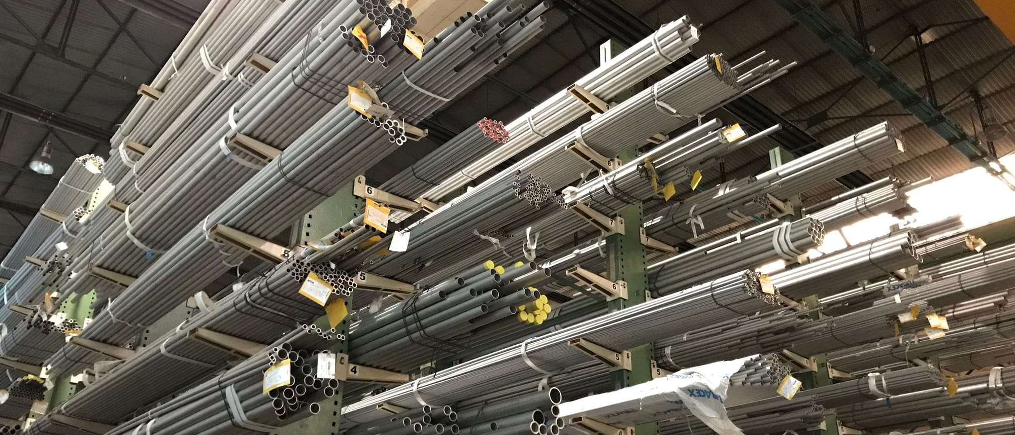 Kragarmregal in einem Großhandelslager, darauf gebündelte Metallrohre in vielen Längen und Durchmessern.